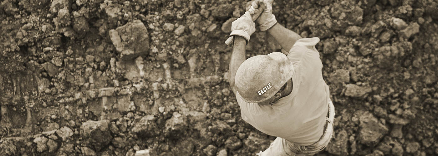 A Castle construction worker swings a sledge hammer.