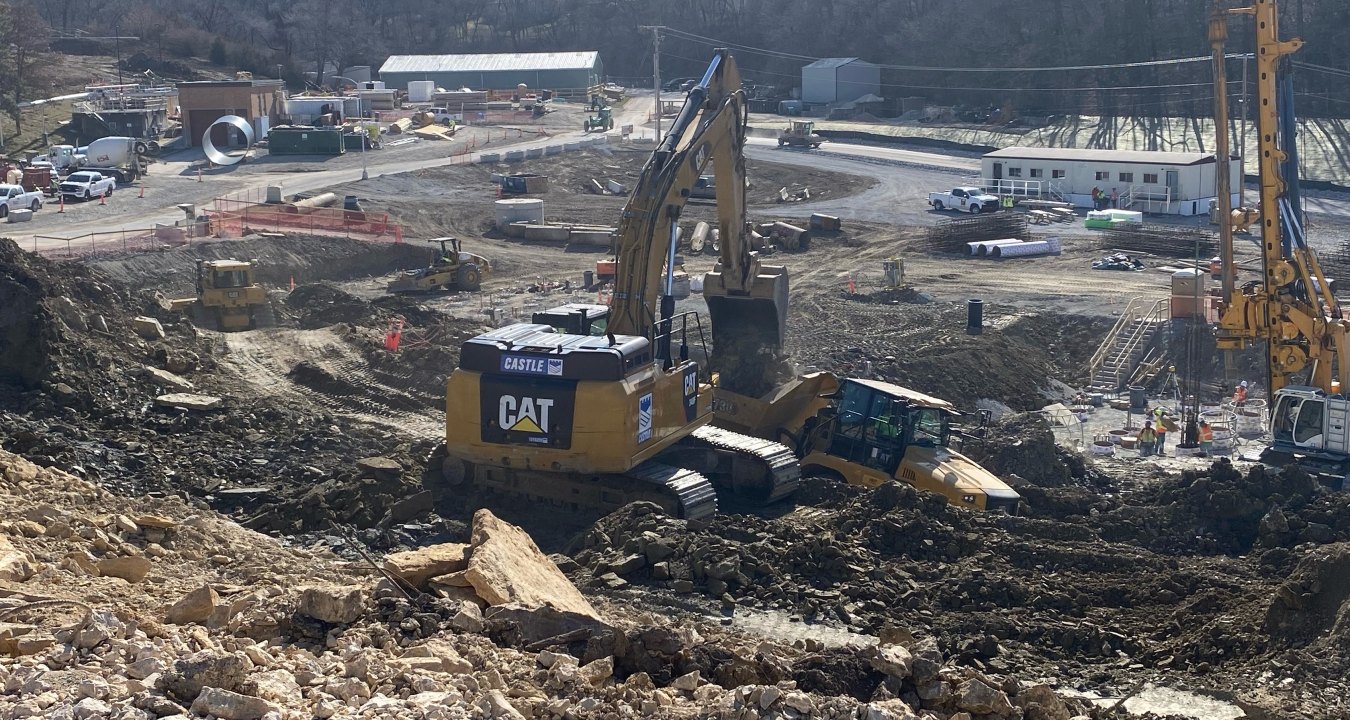 Active construction site with yellow excavator, bulldozer, pile boring machine