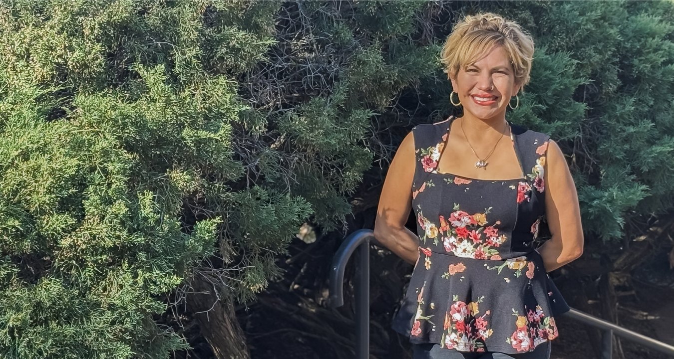 Abigail Garcia standing outside with green foliage background