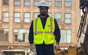 Brent Aden in PPE standing on dozer track system