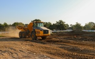 Yellow John Deer dump truck driving across project site