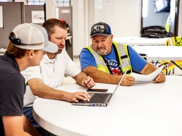 Three people looking at a laptop screen