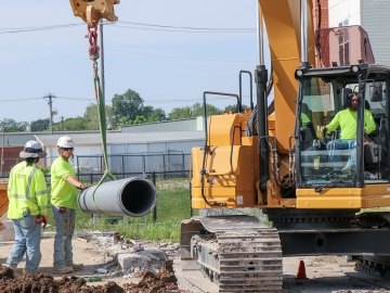 Excavator picking up pipe