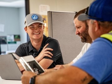 Three smiling Castle employees working on laptops