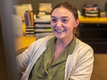 A person smiling and looking at a computer screen.