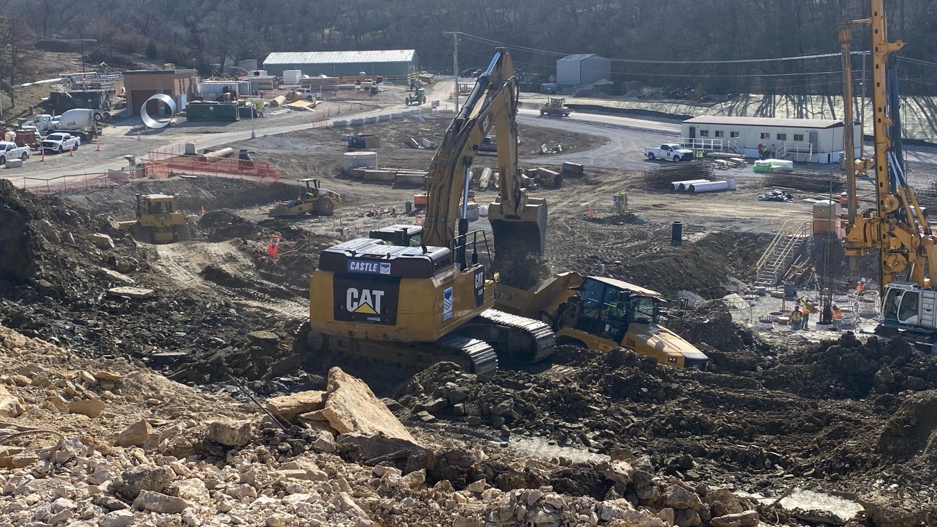 Active construction site with yellow excavator, bulldozer, pile boring machine