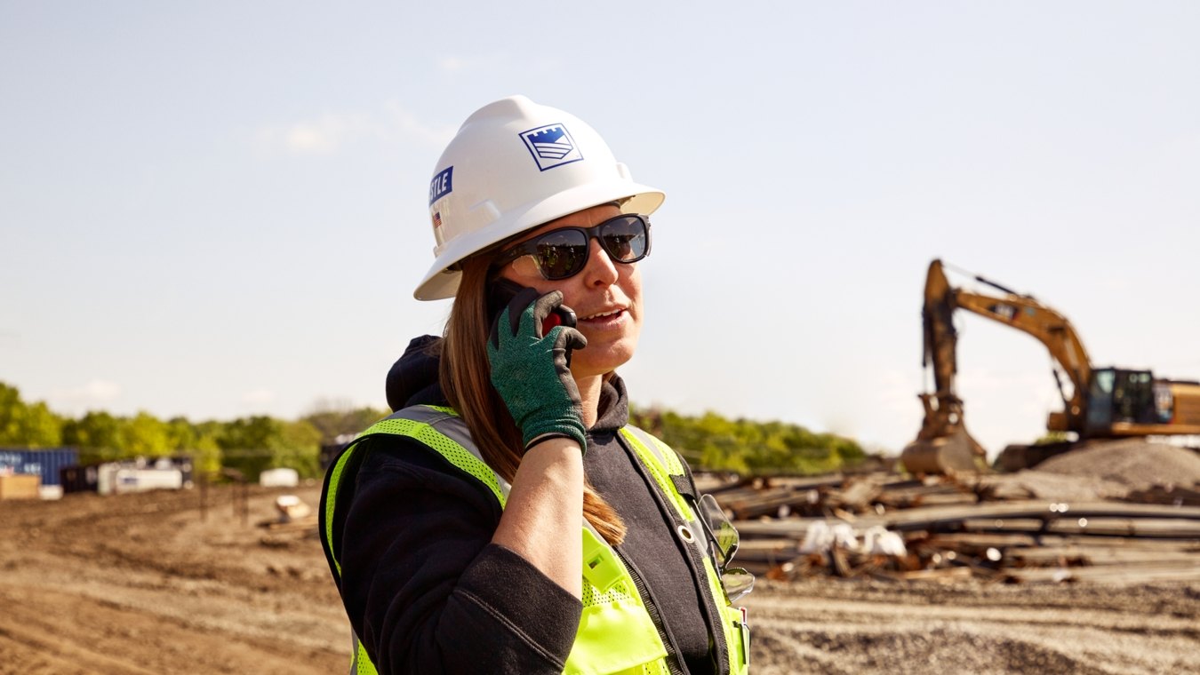 Castle Contracting field employee on jobsite and talking via cell phone
