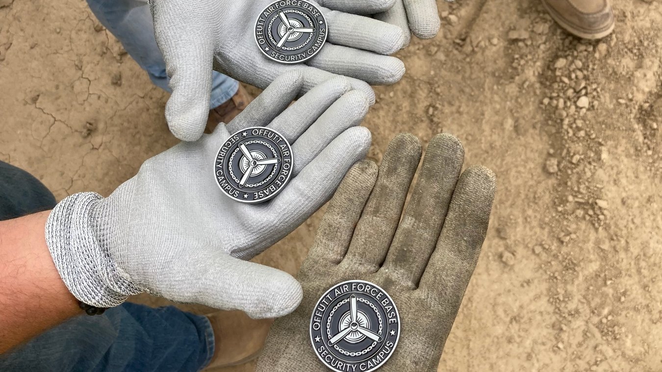 Open hands palms facing up holding Offutt Air Force Base medallions