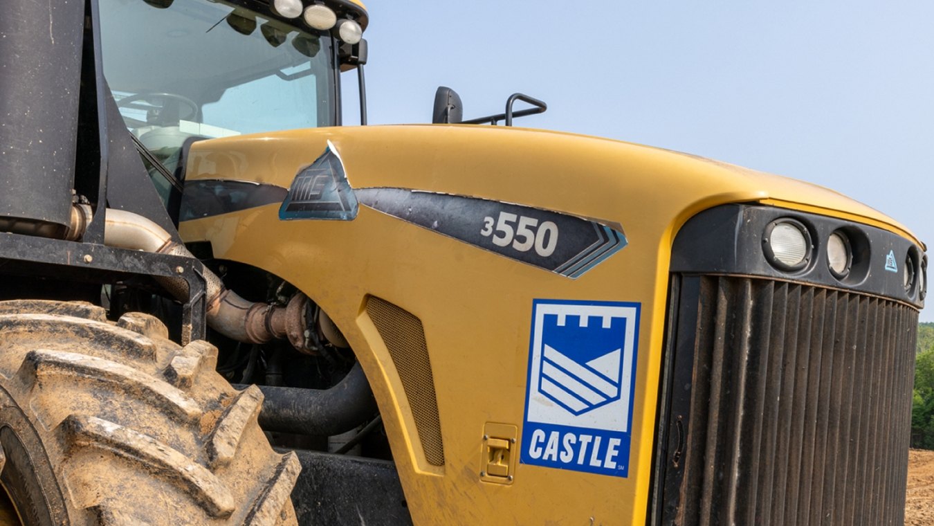 Yellow construction tractor with Castle Contracting logo on construction site