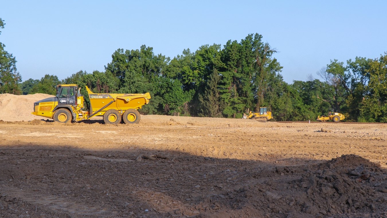 Wide project site with yellow heavy equipment and dump truck