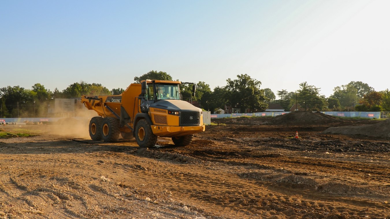 Yellow John Deer dump truck driving across project site