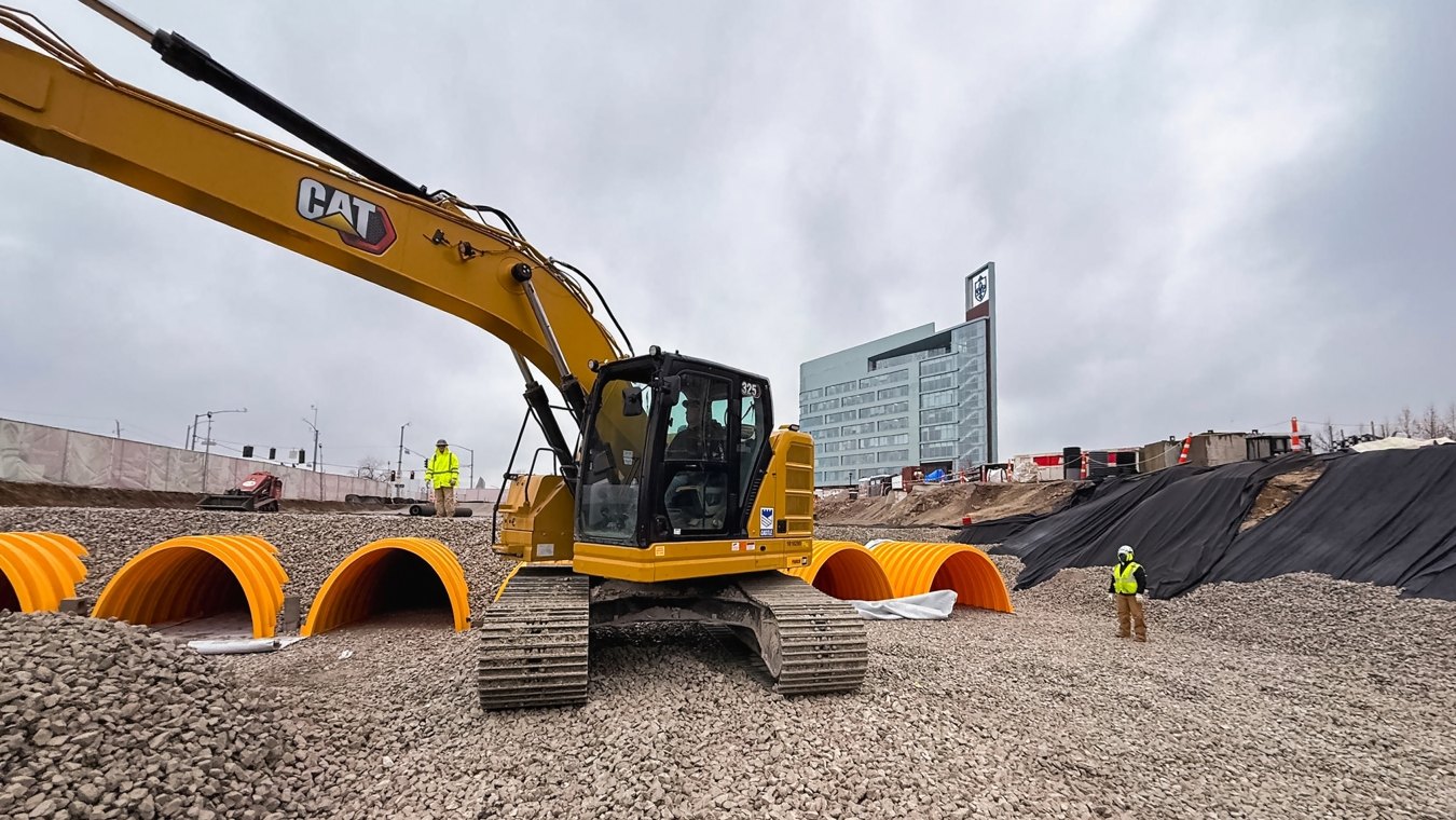 Construction site with excavator and partially buried stormwater drainage chambers