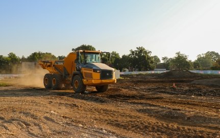 Yellow John Deer dump truck driving across project site