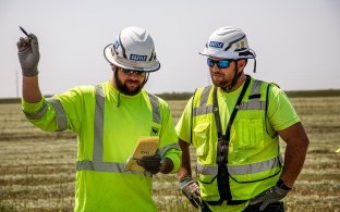 Two people looking at a piece of paper while in the field