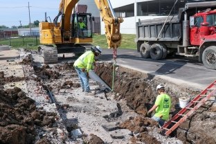 people working in trench with excavator