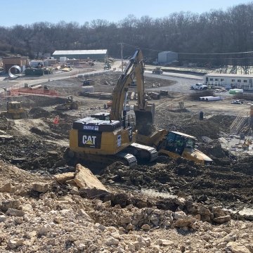 Active construction site with yellow excavator, bulldozer, pile boring machine