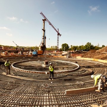 Tower crane behind construction workers and iron rebar rods