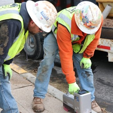 Two construction workers in PPE measuring directional boring pipe depth