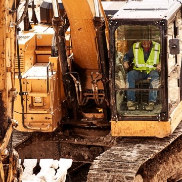 Construction worker operating CAT excavator close-up