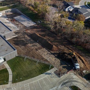Arial drone shot of excavator, hauling truck, and earthwork