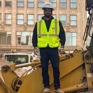 Brent Aden in PPE standing on dozer track system