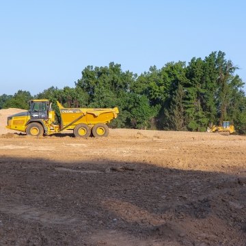 Wide project site with yellow heavy equipment and dump truck