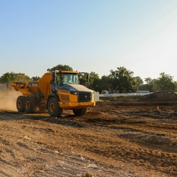 Yellow John Deer dump truck driving across project site