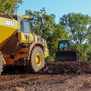 Yellow John Deer dump truck facing dozer on project site