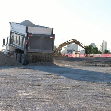 Dump truck, excavator and construction worker on construction site with the St. Louis city skyline in the background