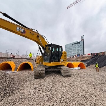 Construction site with excavator and partially buried stormwater drainage chambers