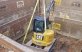CAT yellow excavator lowered in utilities pit